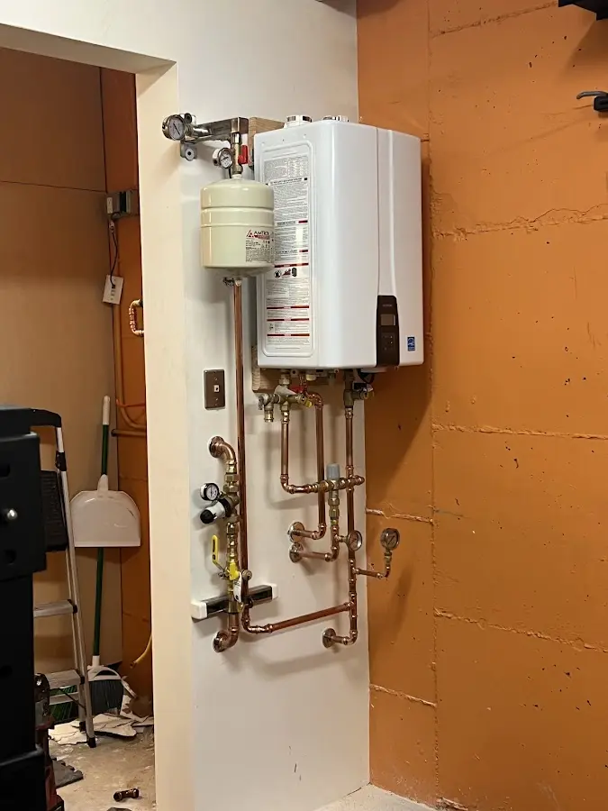 Plumbing technician inspecting water heater connections in Finley
